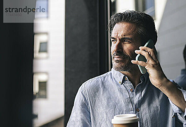 Männlicher Berufstätiger telefoniert beim Kaffeetrinken im Hotelzimmer