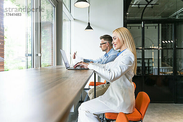 Männliche und weibliche Kollegen nutzen Laptop während der Arbeit im Büro
