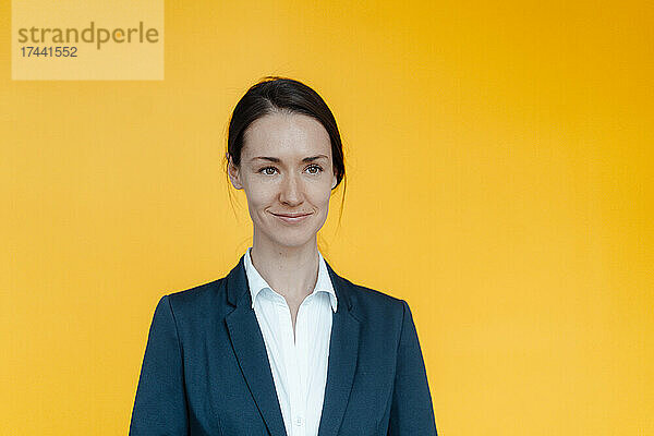 Lächelnde Geschäftsfrau vor gelbem Hintergrund