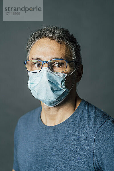 Reifer Mann trägt während einer Pandemie im Studio eine schützende Gesichtsmaske