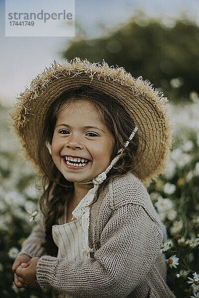 Fröhliches Mädchen mit Hut auf dem Blumenfeld