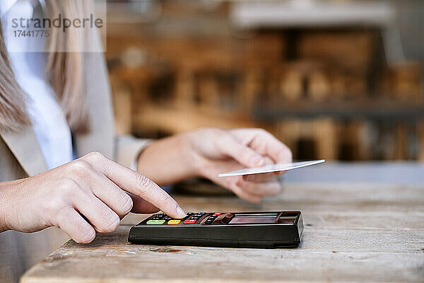 Junge Geschäftsfrau zahlt am Cafétisch mit Kreditkarte