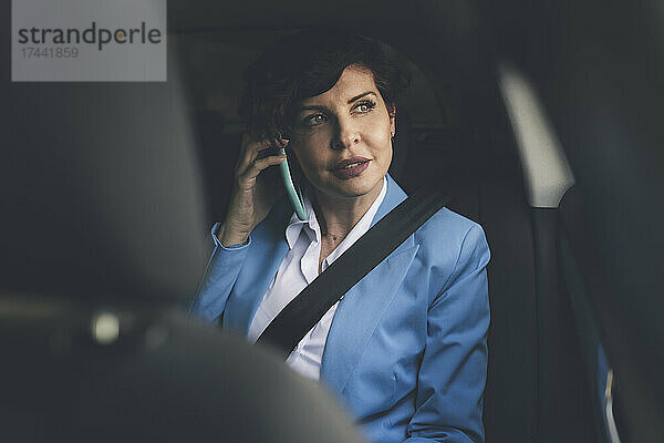 Reife Geschäftsfrau telefoniert  während sie im Auto sitzt