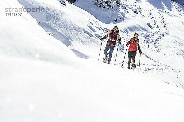Mann und Frau wandern beim Schneeschuhwandern im Schnee