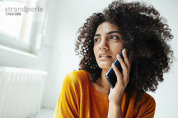 Afro-junge Frau  die zu Hause mit dem Handy telefoniert