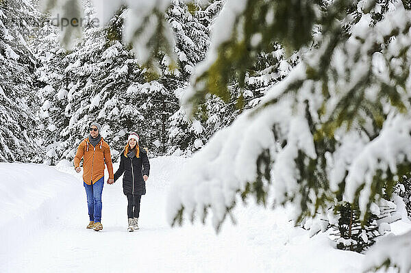 Mann und Frau genießen ihre Freizeit beim Spazierengehen im Schnee im Winter