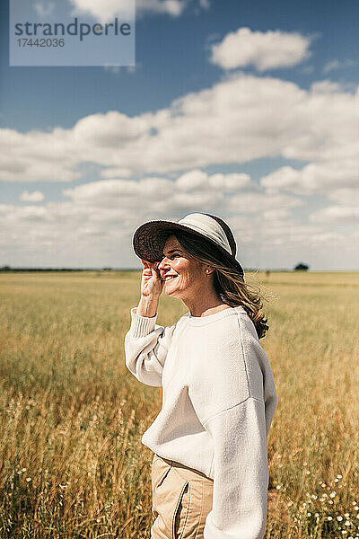 Lächelnde reife Frau mit Hut auf dem Feld