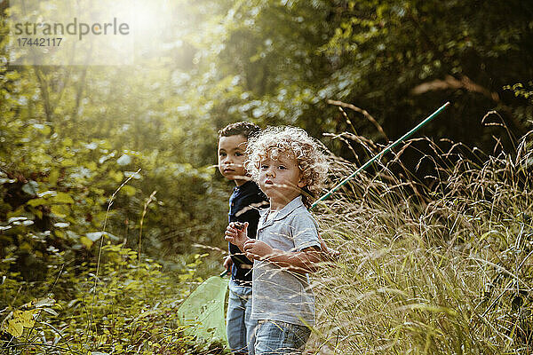 Jungen stehen an sonnigen Tagen zusammen im Wald