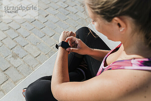 Sportlerin überprüft an sonnigen Tagen die Zeit auf der Smartwatch