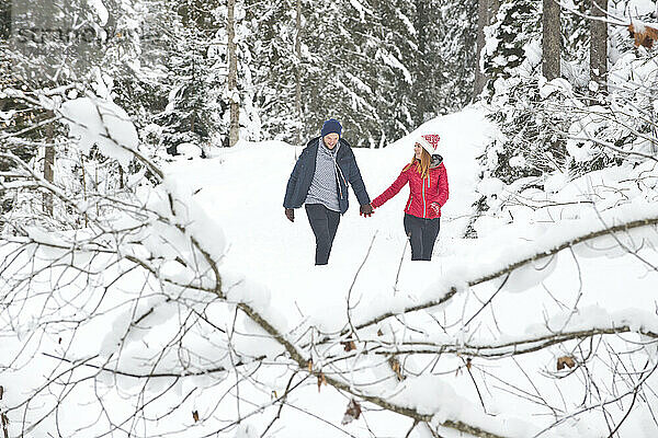 Paar hält Händchen beim Gehen im Schnee im Winter