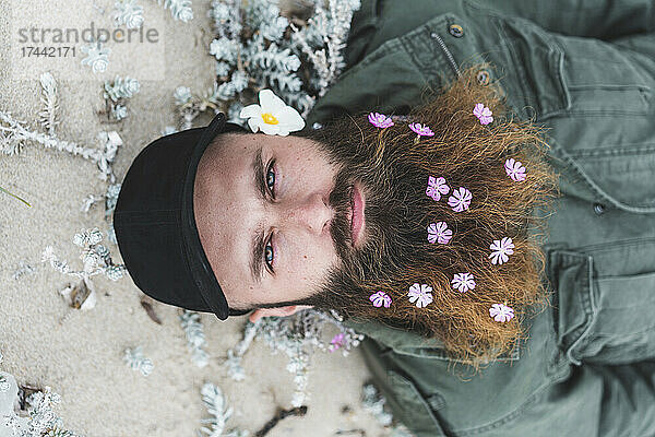 Hipster-Mann mit Blumen im Bart liegend
