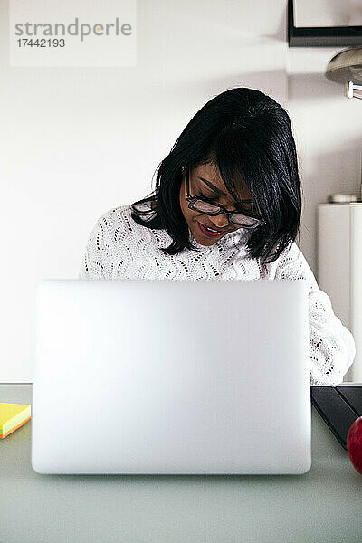 Berufstätige Frau trägt eine Brille  während sie am Schreibtisch sitzt