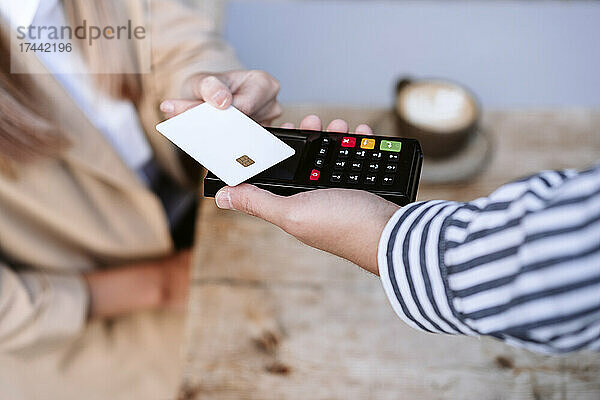 Geschäftsfrau bezahlt per Kreditkarte an den Kellner im Café