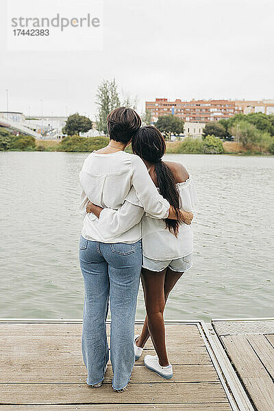 Lesbisches Paar mit Armen und Blick auf den See