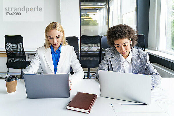 Weibliche Kollegen nutzen Laptops während der Arbeit im Büro