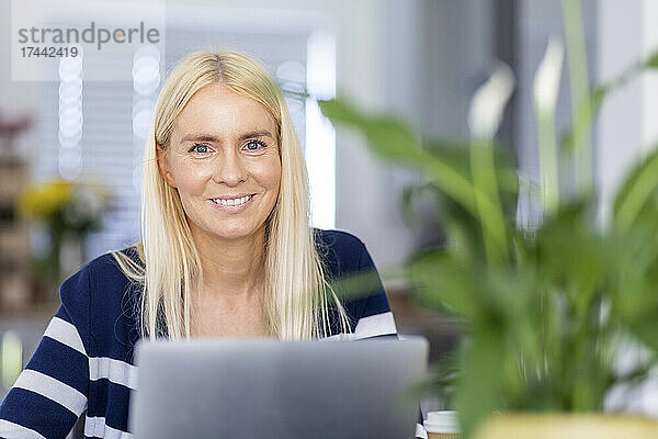 Lächelnde blonde Freiberuflerin im Heimbüro