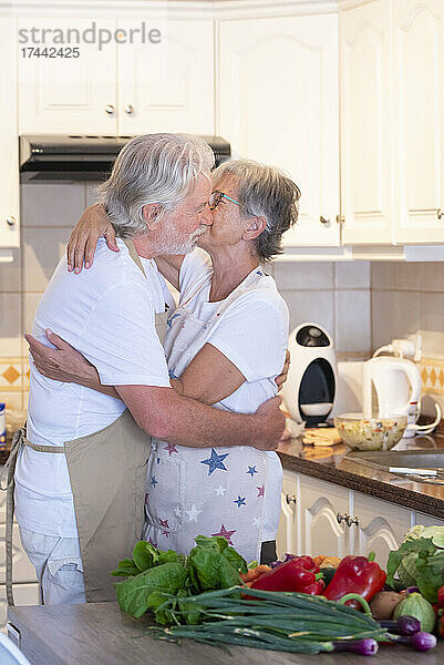 Älteres Paar umarmt sich zu Hause in der Küche