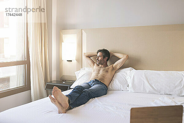 Mann ohne Hemd entspannt sich im Hotelzimmer
