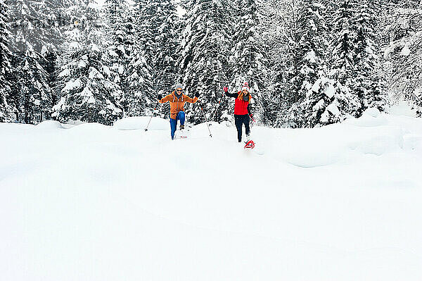Mann und Frau beim Schneeschuhwandern im Winter