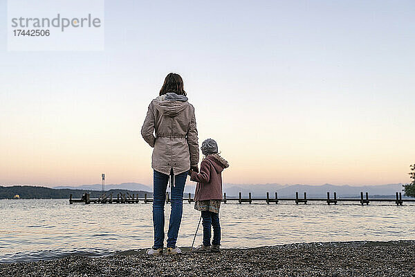 Mutter und Tochter halten Händchen  während sie an der Küste stehen