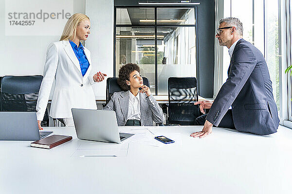 Geschäftsmann hört weiblichen Kollegen zu  die während eines Treffens im Büro diskutieren