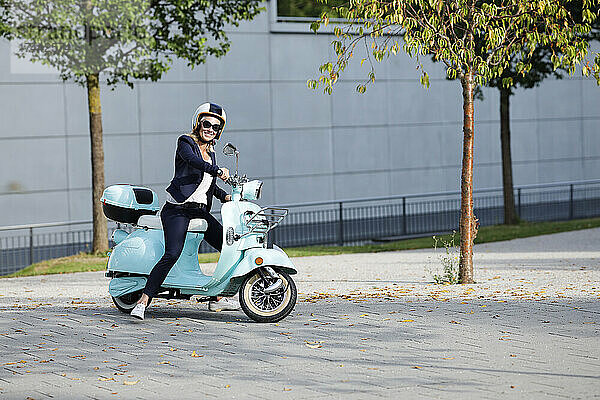 Lächelnde Geschäftsfrau  die Motorroller fährt
