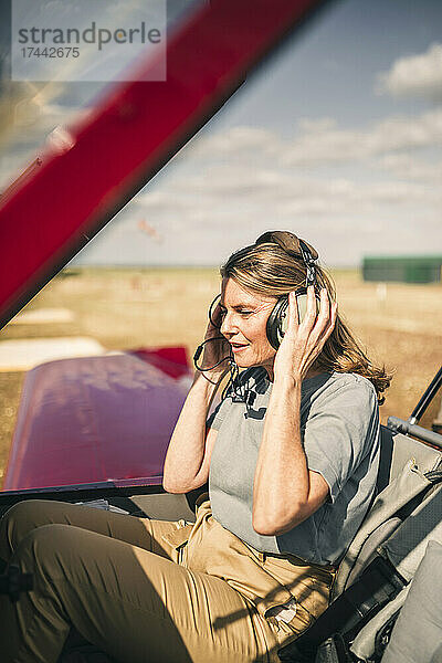 Frau hört im Flugzeug über Kopfhörer zu