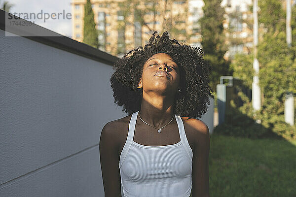 Afro-Frau mit dem Kopf an der Wand und genießt die Sonne