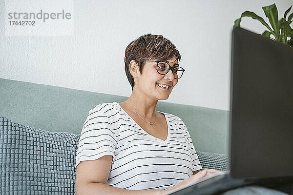 Frau mit Brille und Laptop im heimischen Bett