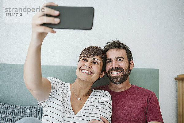 Lächelndes Paar macht zu Hause ein Selfie mit dem Smartphone
