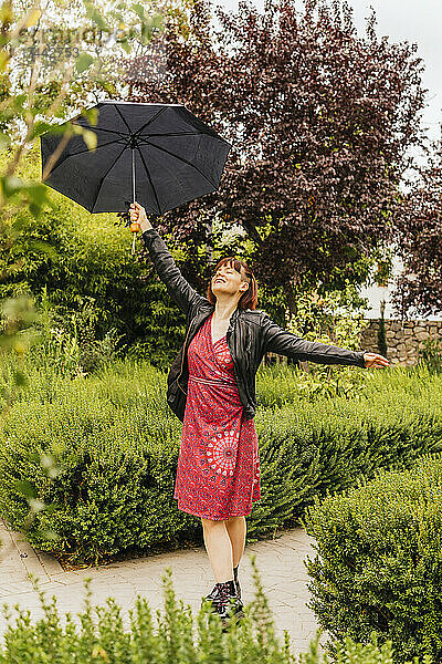 Frau mit Regenschirm genießt regnerischen Tag im Park