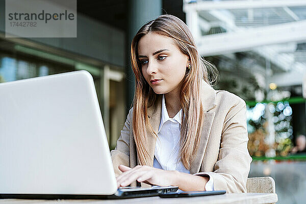 Geschäftsfrau mit Laptop auf der Café-Terrasse