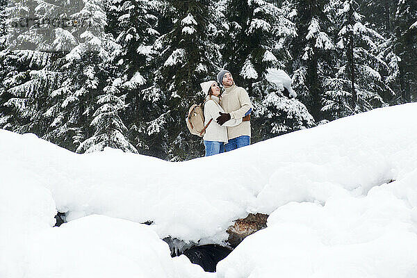 Freundin umarmt Freund im Wald bei Schnee