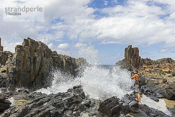 Australien  New South Wales  Kiama  männlicher Tourist beim Fotografieren an der geologischen Stätte Bombo Headland Quarry