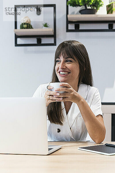 Glückliche Geschäftsfrau mit Laptop beim Kaffee im Restaurant