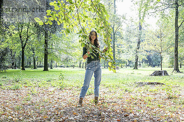 Frau hält Zweige  während sie im Park steht