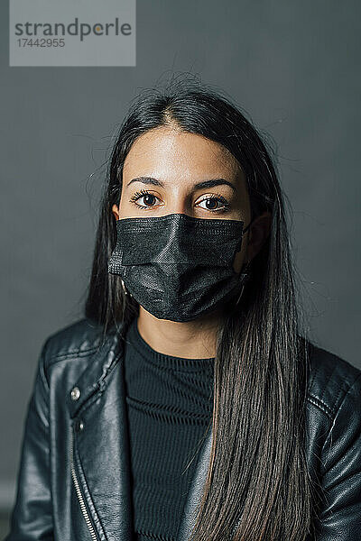 Junge Frau trägt während COVID-19 eine schützende Gesichtsmaske
