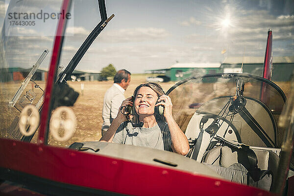 Lächelnde Frau mit Kopfhörern im Propellerflugzeug