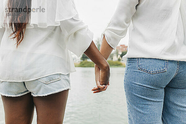 Freundinnen halten Händchen am Seeufer