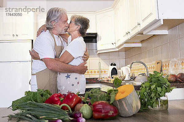 Älteres Paar küsst sich  während es in der Küche steht