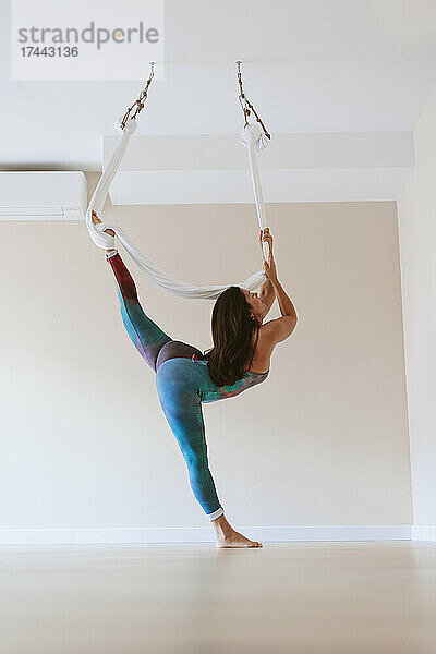 Turnerin praktiziert Aerial Yoga im Studio