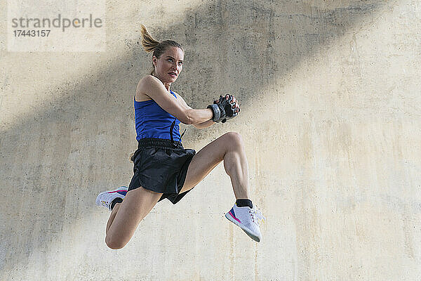 Entschlossene Sportlerin springt beim Training vor der Wand