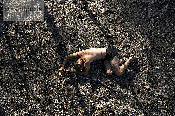 Einsamer Mann liegt auf verbranntem Waldboden