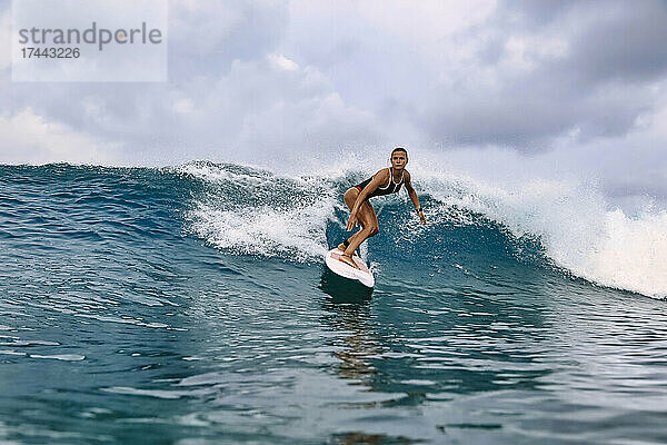 Mittlere erwachsene Frau surft im Urlaub auf dem Wasser