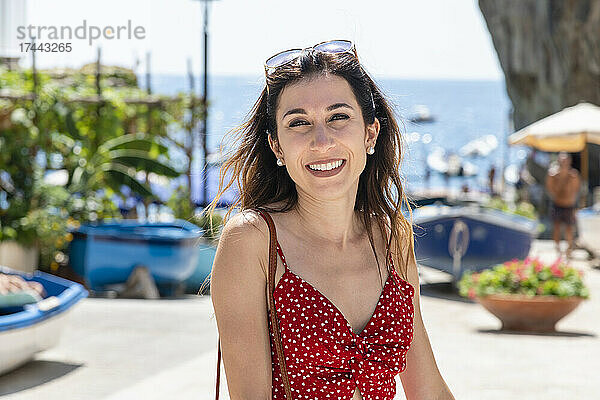 Lächelnde Frau im roten Sommerkleid am Strand