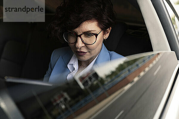 Berufstätige Frau mit Brille sitzt im Auto