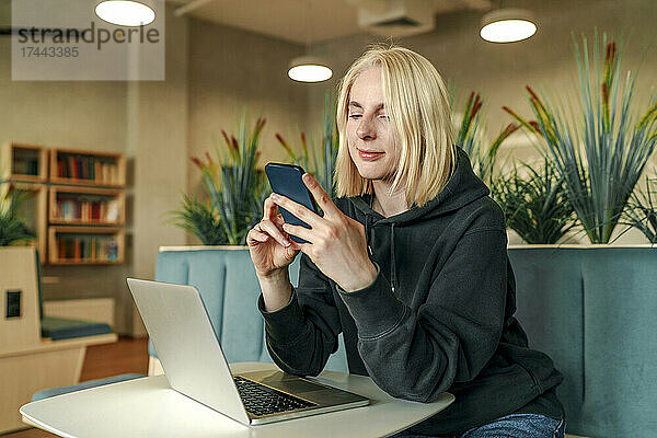Geschäftsfrau mit Laptop auf dem Tisch und Smartphone im Coworking-Büro