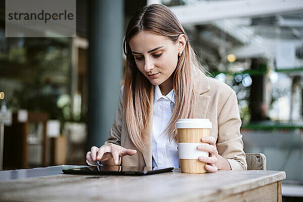 Geschäftsfrau nutzt digitales Tablet am Cafétisch