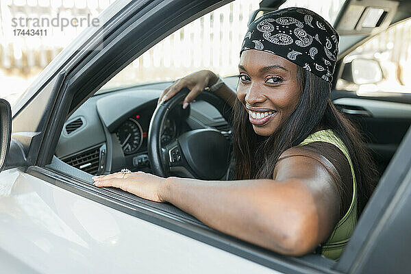 Lächelnde Frau mit Kopftuch sitzt im Auto