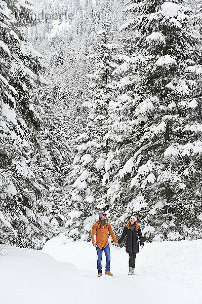 Mann und Frau halten Händchen beim Gehen auf Schnee